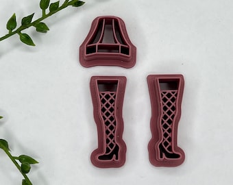 May include: Three pink plastic cookie cutters: a lampshade, and two pairs of legs with fishnet stockings.
