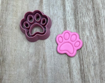 May include: A pink plastic paw print cookie cutter and a pink clay paw print.