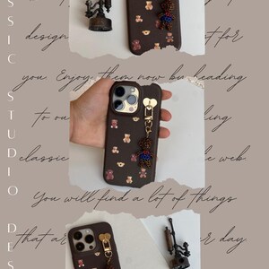 May include: A brown phone case with a gold heart-shaped clasp and a teddy bear charm. The case is adorned with small teddy bear motifs. An antique-style decorative object is also visible.