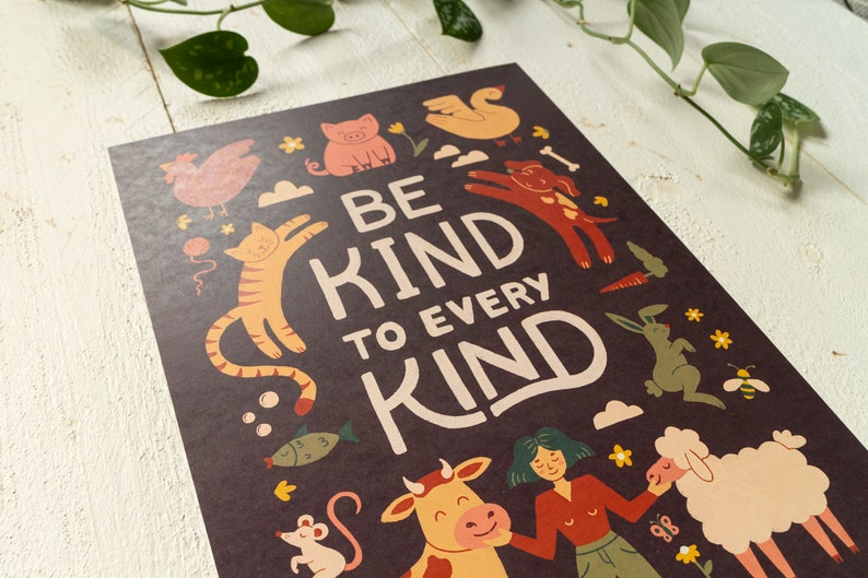 May include: A dark brown poster with the words "BE KIND TO EVERY KIND" in large, cream-colored letters. The poster features illustrations of various animals, including a cat, dog, pig, and sheep, in a whimsical style.