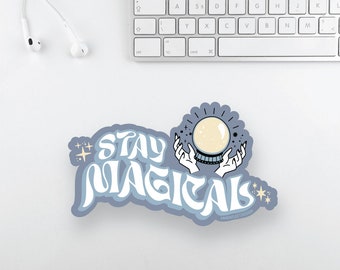 Może przedstawiać: Niebieska naklejka z tekstem "STAY MAGICALS" w retro czcionce. Naklejka przedstawia kryształową kulę z gwiazdami i rękami, które ją trzymają.