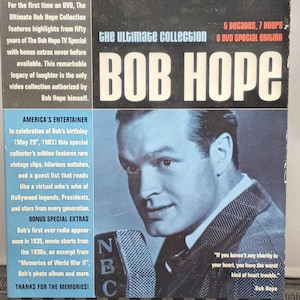 Puede incluir: DVD de The Ultimate Bob Hope Collection. La portada es negra y gris con "BOB HOPE" en letras blancas grandes. Un retrato en blanco y negro de Bob Hope está a la derecha. El texto incluye "5 décadas, 7 horas, 3 DVD edición especial."