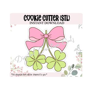 May include: A pink bow and two green shamrocks cookie cutter design. The text "COOKIE CUTTER (STL) INSTANT DOWNLOAD" is at the top. The text "Digital Creative Cuts" is on the image. The text "*No physical item will be shipped to you*" is at the bottom.