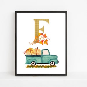 Puede incluir: Una impresión de arte imprimible con un camión azul con una letra "E" de cuadros y hojas de otoño. El camión lleva calabazas y conduce por un campo de hierba.