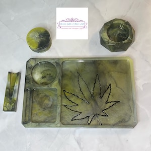 May include: A green and black marble rolling tray with a leaf design, a small round container, a rectangular tray, and a hexagonal ashtray.