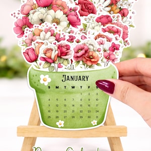 May include: A desk calendar for January, shaped like a flower pot filled with pink, red, and white flowers. The calendar is on a small wooden easel. The text "Desk Calendar" and "Digital Download" are at the bottom.