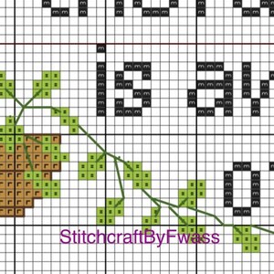 May include: Cross stitch pattern featuring a brown acorn with green leaves and the text "Dream Big" in black.