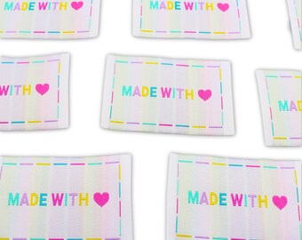 May include: A set of six white fabric labels with rainbow stripes and the text "MADE WITH" and a pink heart. The labels are perfect for adding a handmade touch to your crafts.