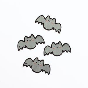 May include: Four gray felt iron-on patches of cute cartoon bats with pink cheeks. Each bat has a small "SA" embroidered on the bottom.