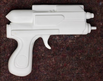 May include: A white plastic toy gun with a barrel and a handle. The gun has a futuristic design.