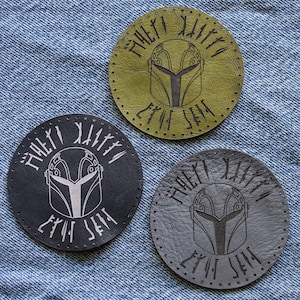May include: Three round leather patches with a Mandalorian helmet design and the text "This is the Way" in a circular pattern around the helmet. The patches are in black, gray, and green.