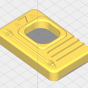 May include: A yellow rectangular object with a central rectangular opening. The object has a series of parallel lines on one side and a thin, cylindrical element extending from each end. Small circular details and a diagonal line are also present.