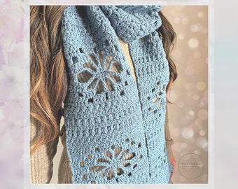 May include: A light blue crochet scarf with a delicate floral pattern. The scarf is worn around the neck of a person with long brown hair.
