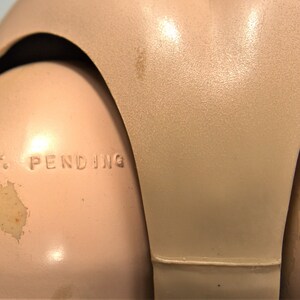 Op de afbeelding: Close-up van een schoudergewricht van een vintage pop met de tekst "PAT. PENDING" in reli&euml;f op de kunststof.