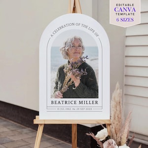 Op de afbeelding: Een wit herdenkingsbord op een ezel met de tekst "A CELEBRATION OF THE LIFE OF" en "BEATRICE MILLER". Het bord bevat een foto van een vrouw die bloemen vasthoudt. Er staan ook de data "15 JUL 1962 ~ 29 SEP 202X" en de tekst "EDITABLE CANVA TEMPLATE 6 SIZES".