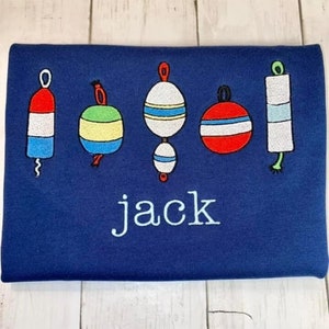 May include: A navy blue t-shirt with five embroidered nautical buoy designs in red, white, blue, green, and yellow. The word "jack" is embroidered in white below the buoys.