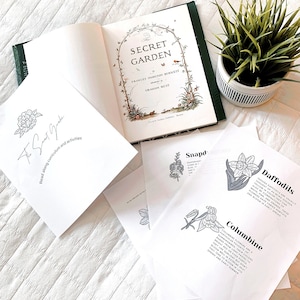 May include: A white book with the title "The Secret Garden" by Frances Hodgson Burnett, illustrated by Graham Rust. The book is open to a page with a colorful illustration of a garden. There are also several white sheets of paper with black and white illustrations of flowers and text about the flowers.