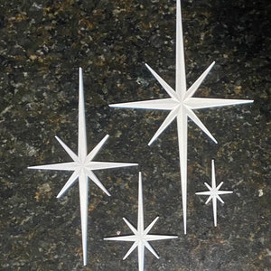 May include: Four white starburst shapes on a dark gray background. The text "Pearl White" is at the top of the image.