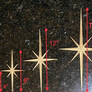 May include: Four gold starburst ornaments of varying sizes. The smallest is 4 inches tall, the next is 8 inches tall, the next is 12 inches tall, and the largest is 16 inches tall.