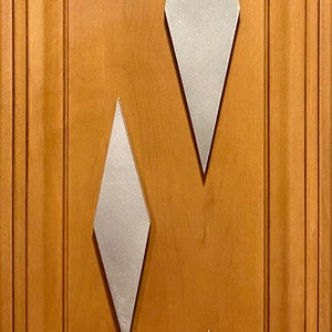 May include: Three silver diamond-shaped wall decor pieces on a wood panel background. The diamonds are different sizes, with the largest at the top and the smallest at the bottom.