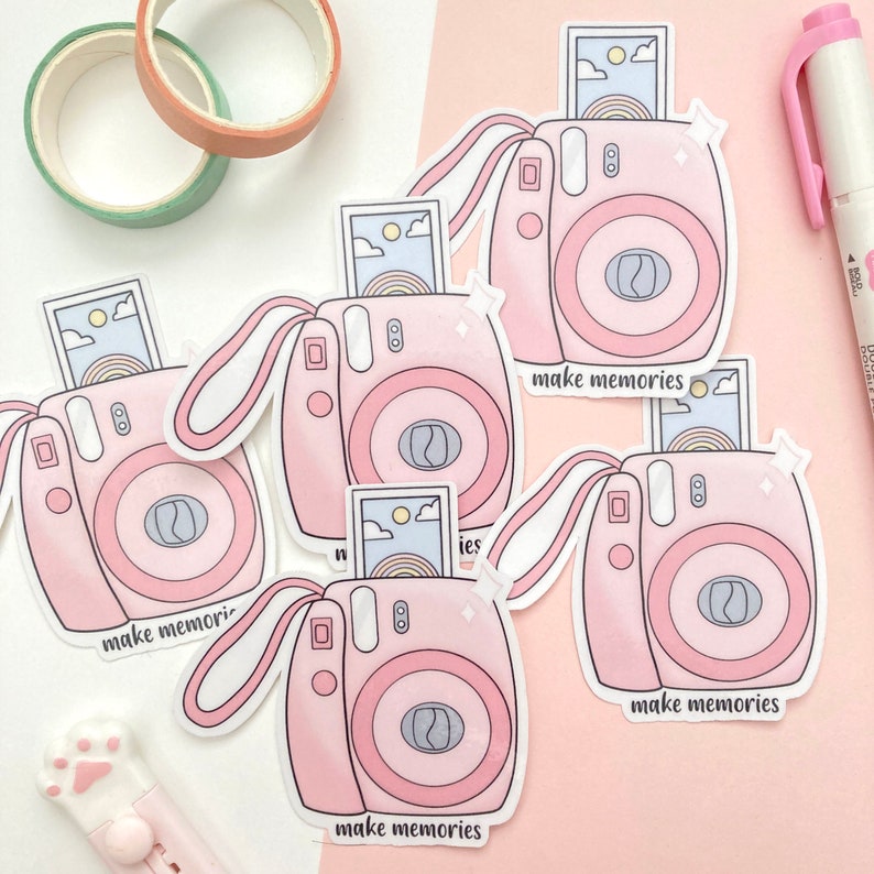 May include: Four pink and white instant camera stickers with a photo inside each camera. Each sticker has the text "make memories" printed on it.
