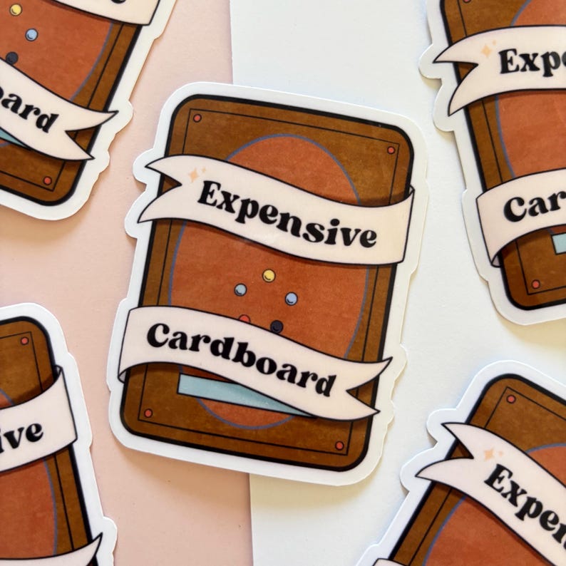 Puede incluir: Una pegatina con un fondo marr&oacute;n y naranja, con las palabras "Expensive" y "Cardboard" en una pancarta blanca. La pegatina tiene forma rectangular con esquinas redondeadas y un fondo rosa claro.