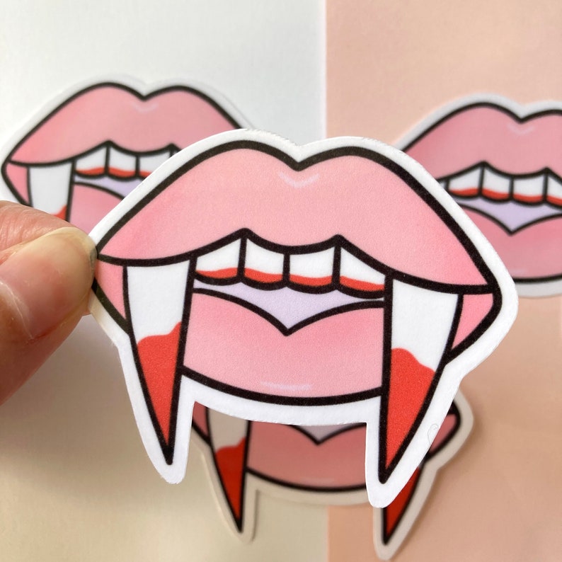 May include: Pink lips with sharp white fangs and red dripping blood.  The fangs are outlined in black.  The lips are outlined in black.