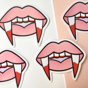 May include: Four pink and white vampire mouth stickers with fangs. The stickers are on a white and pink background.
