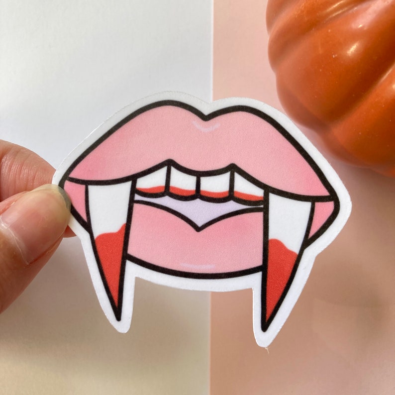 May include: Pink lips with white fangs and red dripping blood. Halloween themed sticker.