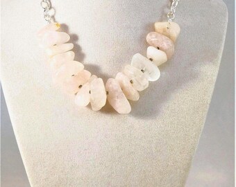 Collar artesanal de cristal de cuarzo rosa con ajuste regulable sobre una cicatriz en el cuello.