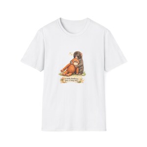 Könnte beinhalten: Weißes T-Shirt mit einer Grafik von zwei sich umarmenden Affen. Ein Affe ist braun, der andere grau. Der Text "A little kindness goes a long way" steht unter den Affen.