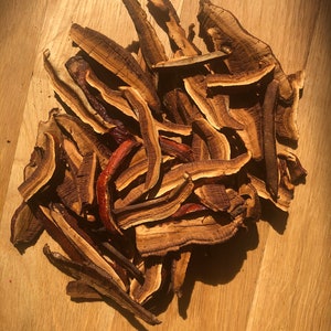 May include: A pile of dried, brown and reddish-brown reishi mushrooms.