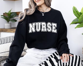Puede incluir: Sudadera negra con texto blanco que dice "NURSE" en una fuente universitaria.