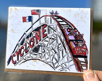 May include: A watercolor illustration of a roller coaster called "CYCLONE CONEY ISLAND" with three cartoon mice riding it. The roller coaster is red and white with a black track. The background is white with yellow and brown splatters.