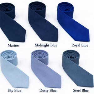 Puede incluir: Seis corbatas enrolladas dispuestas en dos filas, con varios tonos de azul. La fila superior incluye Marine, Midnight Blue y Royal Blue. La fila inferior incluye Sky Blue, Dusty Blue y Steel Blue. Cada corbata tiene un extremo puntiagudo.