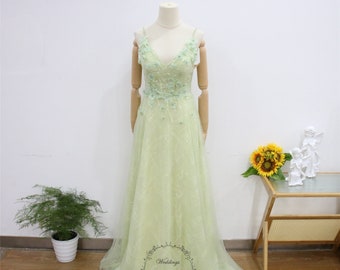 Puede incluir: Un vestido de tul verde claro con escote en V y delicado bordado floral. El vestido tiene un corpiño ajustado y una falda fluida.