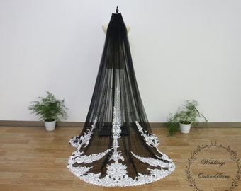 May include: A black tulle wedding veil with white lace trim. The veil is long and flowing, and the lace trim is delicate and intricate.