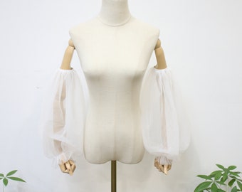 May include: White sheer tulle fabric sleeves with elastic at the top and bottom. The sleeves are gathered at the wrist and are long and flowing.
