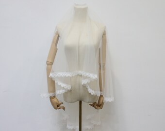 May include: A white bridal veil with a delicate lace trim. The veil is made of soft tulle and is perfect for a wedding ceremony.