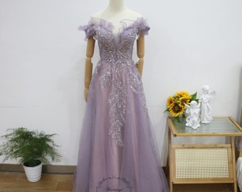 May include: A lavender off-the-shoulder gown with a beaded bodice and a tulle skirt. The gown is on a mannequin and has a ruffled neckline.