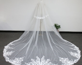 May include: A white bridal veil with a scalloped edge and floral lace trim. The veil is long and flowing, with two layers.
