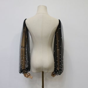 May include: Black sheer mesh sleeves with pearl embellishments. The sleeves are long and have a gathered cuff.