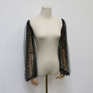 May include: Black sheer mesh sleeves with pearl embellishments. The sleeves are long and have a gathered cuff.