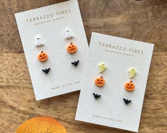 May include: Two sets of Halloween-themed stud earrings on white cards. Each set includes a white ghost, an orange jack-o'-lantern, and a black bat. The cards read "TERRAZZO VIBES handmade jewelry" and "MADE IN THE USA".
