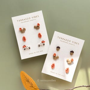 May include: Two cards of handmade jewelry with fall-themed designs. Each card features earrings shaped like squirrels, leaves, acorns, and pumpkin trucks. The cards read "TERRAZZO VIBES handmade jewelry" and "MADE IN THE USA."