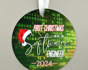 Może przedstawiać: Okrągła zielono-czarna ozdoba choinkowa z czerwoną czapką Świętego Mikołaja i tekstem "FIRST CHRISTMAS as a SOFTWARE ENGINEER - 2024 - "