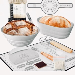May include: A collection of baking tools and ingredients for making bread. Includes a white bowl with a loaf of bread, a measuring cup, a dough scraper, a baking mat with measurements, and a bag of flour. The bread is golden brown.
