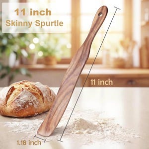 Puede incluir: Una espátula fina de 28 cm hecha de madera marrón con un patrón de grano visible. La herramienta de cocina presenta un diseño largo, plano y cónico con un orificio en el extremo del mango. El texto en la imagen dice 11 inch Skinny Spurtle.