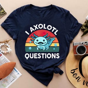 Könnte beinhalten: Ein marineblaues T-Shirt mit einer Retro-Sonnenuntergangsgrafik mit einem Axolotl und dem Text "I axolotl questions".