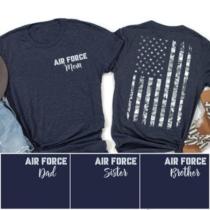 May include: Navy blue t-shirts with a white camouflage American flag design on the back and text on the front. The text on the shirts reads "Air Force Mom", "Air Force Dad", "Air Force Sister", and "Air Force Brother".
